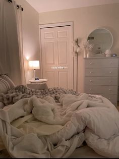 an unmade bed with blankets and pillows on it in a bedroom next to a dresser