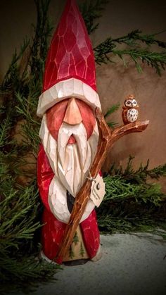 a red and white gnome with an owl sitting on a branch next to it's head