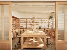 an empty room with wooden shelves and chairs in the center, as seen through glass doors