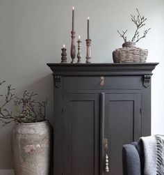 a black cabinet with candles on top of it and two vases next to it