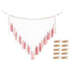 the pink and white tasselled garland is hanging from strings with wooden pegs