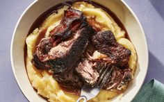 a bowl filled with meat and mashed potatoes on top of a blue table cloth