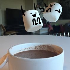 a cup of hot chocolate with marshmallows in the shape of two marshmallows