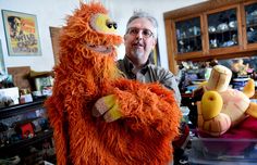 a man standing next to an orange stuffed animal