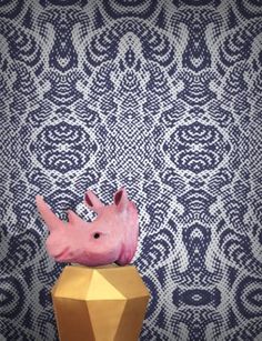 a pink bird sitting on top of a golden vase in front of a blue and white wall