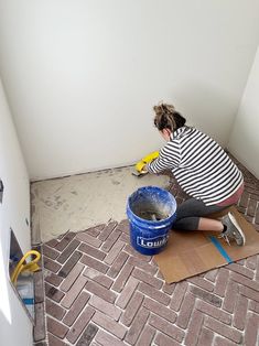 a woman kneeling down on the floor with a bucket