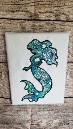 an embroidered applique on the side of a wooden wall, depicting a sea horse