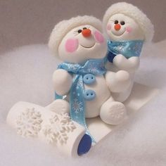 two snowmen sitting next to each other on top of white fluffy blanketed ground