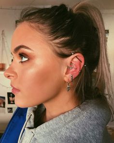 a woman wearing ear piercings and looking off into the distance