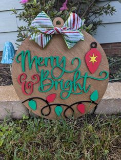 a wooden sign that says merry and bright with ornaments on it in front of a house