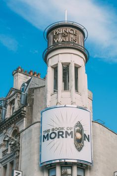 the book of mormon sign is on display in front of a building with a clock tower