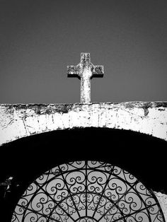 a black and white photo of a cross on top of a building with a window