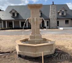 a water fountain in front of a large house on the side of a road that is under construction