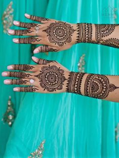 two women with henna tattoos on their hands, one is wearing a blue dress