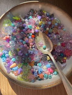 a bowl filled with lots of different colored beads and a spoon on top of it