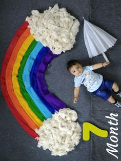 a young boy laying on the ground next to a rainbow cake