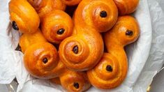 a bunch of doughnuts that are in a white bowl on some wax paper