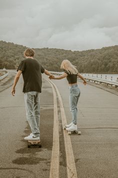 a man and woman skateboarding down an empty road