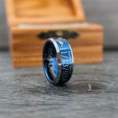 a blue ring with an arrow engraved on it sitting in front of a wooden box