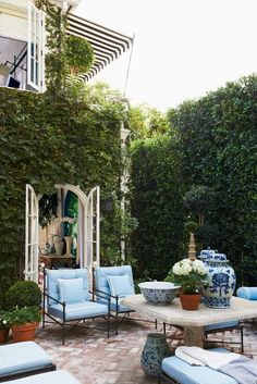 an outdoor patio with blue and white furniture, potted plants and trees in the background