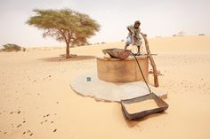 a man sitting on top of a barrel in the desert