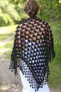 a woman wearing a black crocheted shawl with an open back and sleeves