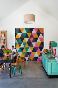 two people sitting at a table in front of a colorful wall