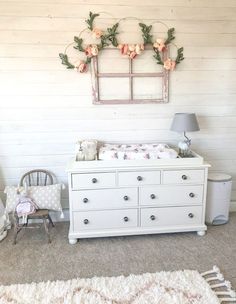 a baby's room with a dresser, crib and flowers on the wall