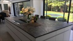 a kitchen counter with flowers in a vase on it and an open door leading to the back yard