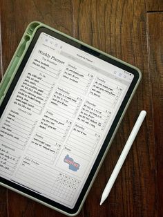 a tablet sitting on top of a wooden table next to a pen