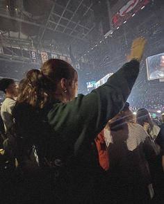 two people standing in front of a crowd at a basketball game with their arms up