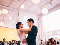 a bride and groom sharing their first dance at the wedding reception in front of an audience