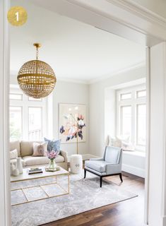 a living room filled with furniture and a chandelier hanging over the top of it