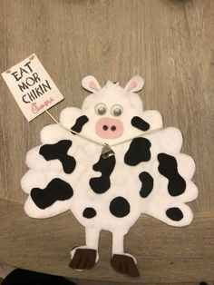 a cow with a sign that says eat more china on it's back hanging from a door