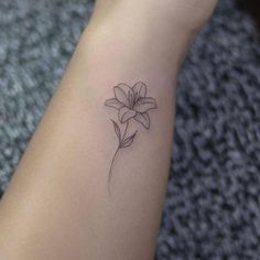 a small flower tattoo on the wrist is shown in black and grey ink, with a single lily at the center