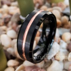 a black and rose gold wedding ring on rocks