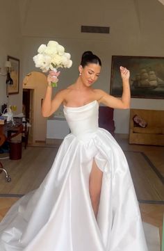 a woman in a white wedding dress holding flowers