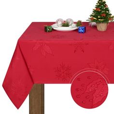 a red table cloth with christmas decorations on it and a small tree in the center