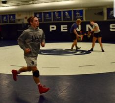 a man running on a wrestling ring with other people in the back ground behind him