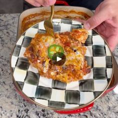 a person is cutting into some food on a checkered plate with a knife and fork