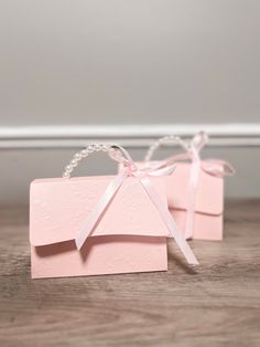 two pink gift boxes tied with white ribbon