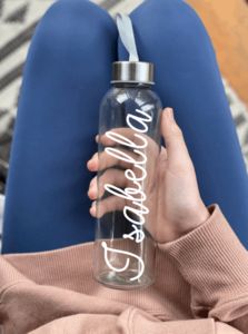 a woman is holding a water bottle with the word love on it in white writing