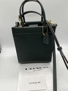 A buttery soft glovetanned leather mini tote based on the iconic "Cashin Carry" from 1969. Perfect for night outs! Coach Mini Cashin Tote color: amazon green glovetanned leather one credit card slot magnetic snap closure, fabric lining handles with 3" drop detachable strap with 21 1/2" drop for shoulder or crossbody wear four protective feet at base style: C4828Measures 5 1/2" (L) x 6 1/2" (H) x 3" (W) All products sold on suzishop are guaranteed to be authentic. Sale items are purchased directly from authorized dealers or respected industry wholesalers or distributors. Items are never refurbished, factory seconds, or replicas. Brand new, never used, with tag. Not considering offers. Item on hand and ready to ship. Will ship within one business day of received payment. Buyer pays for shipp Green Leather Bag With Snap Closure, Green Style, Pet Home, Mini Tote, Leather Mini, Green Fashion, Sale Items, Snap Closure, Bags Handbags