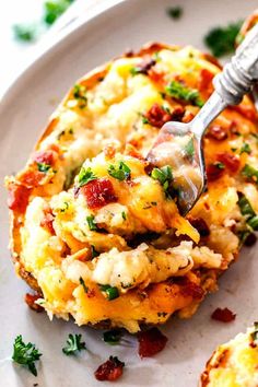 a white plate topped with an omelet covered in cheese and toppings next to a fork