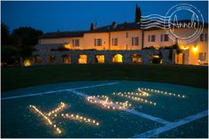 a lit up birthday cake on top of a basketball court in front of a house