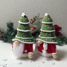 two small crocheted christmas trees sitting next to each other on top of a table