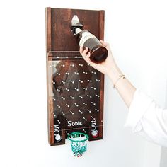 a person holding a bottle in front of a wall mounted game