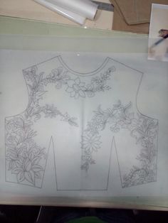 a drawing of a shirt with flowers on it is displayed in front of a white board