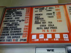 the menu for a fast food restaurant is displayed on an orange and white sign above it