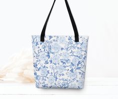 Our classy tote bag features a stunning blue and white chinoiserie pattern of blooming peonies and graceful birds. Crafted from high-quality materials, this tote bag is as durable as it is stylish. Its spacious interior and sturdy handles make it the perfect accessory for carrying all your essentials with ease. Whether you're off to the office or a day out in the garden, this bag will elevate your fashion game. * 100% spun polyester fabric * Bag size: 15″ × 15″ (38.1 × 38.1 cm) * Capacity: 2.6 US gal (10 l) * Maximum weight limit: 44lbs (20 kg) * Dual handles made from 100% natural cotton bull denim * Handle length 11.8″ (30 cm), width 1″ (2.5 cm) * The handles can slightly differ depending on the fulfillment location * Blank product components sourced from China This product is made espec Elegant Blue Bags With Floral Print, Elegant Blue Floral Print Bags, Blue Porcelain Pattern, Porcelain Pattern, Chinoiserie Pattern, Hampton Style, Blue And White Chinoiserie, Floral Tote Bag, Chinese Blue